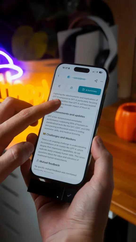 Close-up of hands holding a smartphone displaying an article with an AI Summary tab visible on the screen.